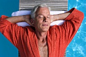 Älterer Mann auf Liege am Swimmingpool