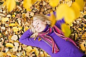 Woman lying in autumn leaves