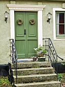 Mit Blumenkränzen geschmückte, grüne Haustür eines schwedischen Wohnhauses