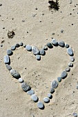 Stones arranged in the shape of a heart in sand