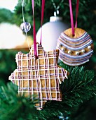 Gingerbread cookies decorated with coloured icing and silver pearls hanging on a Christmas tree