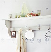 A wooden, shabby chic-style shelf with a row of hooks