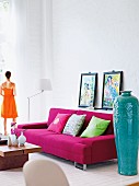 A living room with a high ceiling, a pink sofa and oriental decorative objects