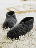 Grey, wool hand-knitted slippers on long-pile rug