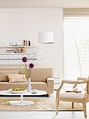 Sofa und Sessel in hellen Farbe und weiße Bogenleuchte vor dem Fenster mit Jalousie