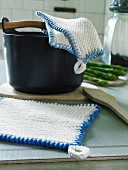 Knitted white pot holders with blue edges