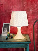 Table lamp with knitted lampshade on blue side table