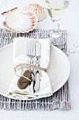 Place setting with name written on pebble and scallop shell as salt cellar