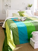 Double bed with striped bedspread in various shades of green