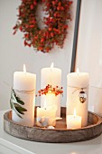 White pillar candles with autumnal decorations on a wooden tray
