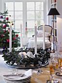 Adventskranz mit silbernem Weihnachtsschmuck und weissen Kerzen auf Tisch