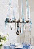 Silver spoons hanging from chandelier above dining table