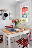 Dining table and red folding chairs in Scandinavian summer house