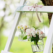 Vases of apple blossom and daisies hanging from ladder