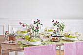 A table set for spring with pink table runners, pastel-green place mats and napkins
