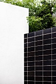 Hausecke mit weiss getünchter Wand und schwarzer Fliesenwand