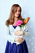 A young woman holding a fabric bag filled with a baguette and a hortensia