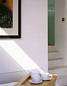 White tea service on a tray beside an open hallway with tiled stair steps