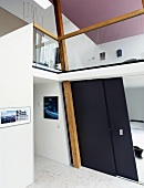 Schwarze Schiebetür im offenem Wohnraum mit Blick auf Galerie und violetter Decke