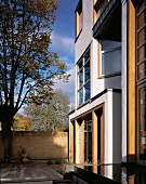 Moderne Hausfassade und Innenhof mit Holzdeck und Wasserfläche