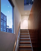 Treppenaufgang vor Wand mit Holzpanelen im Designerstil und Fensterausschnitt mit Blick auf Nachbarhaus