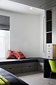 Black upholstered window seat and drawers in a modern bedroom