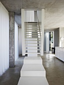 White stair landing in front of stairs in an open living room built of concrete