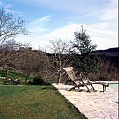 Weather beaten wooden lounger at poolside in a Mediterranean landscape