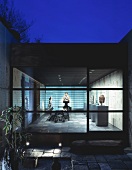 Modern, Japanese home in the evening light with a view through a terrace window into an illuminated exhibition space
