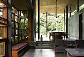 Indian house with traditional wood and glass facade and concrete walls in living room with view of garden