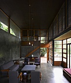 Grey seating in contemporary, open-plan, concrete living room and wood and glass facade with view into garden