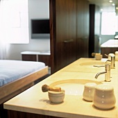 A shaving brush and bathing utensils on a modern wash stand in front of a mirror