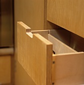 An open cutlery drawer made of light wood with a cut-out handle