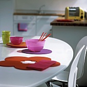 Farbige Glasschalen und Filzauflagen auf weißem Tisch