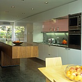 Esssplatz vor freistehendem Küchenblock aus Nussholz in offener Küche mit weisser Front