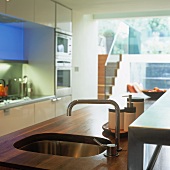 A wooden kitchen work surface with an integrated sink and designer taps