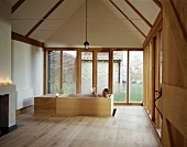 A free-standing wooden bathtub in front of a window in a gable