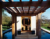 Pergola vor zeitgenössischem Haus im japanischen Stil und Blick durch offene Tür auf Tisch und Hocker