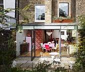 House with brick facade and view into dining room through open, modern terrace doors