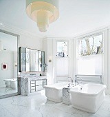 Vintage bathtubs on marble floor with designer ceiling light in spacious, traditional bathroom with bay window
