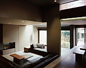 Offener Wohnraum mit tieferliegender Sofalandschaft in Brauntönen mit schlichten Ablagetischen und in Wand integriertem Kamin