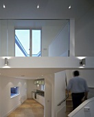 Open-plan house with triangular kitchen next to stairway to higher level with reflection of window