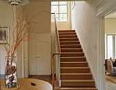 Foyer of English house with sisal stair carpet and vase with gathered natural materials
