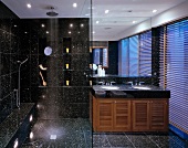 Black speckled tiles in modern bathroom with spotlight effects, ceiling-height mirror and blinds on twilit window