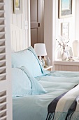 Double bed with light blue pillows near a window