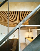 View of modern, open-plan kitchen through metal stairs