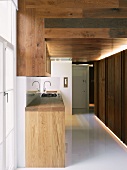 Offene Designerküche mit Küchenzeile aus Massivholz und weißem glänzendem Boden