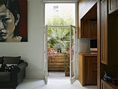 Moderner Wohnraum mit offenen Balkontüren und Blick auf Palmen im Holzbehälter
