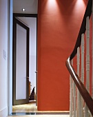 Stairwell with red wall next to open glass door