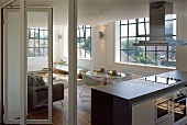 Loftartiger Wohnraum mit Essbereich und freistehendem Küchenblock mit Dunstabzug